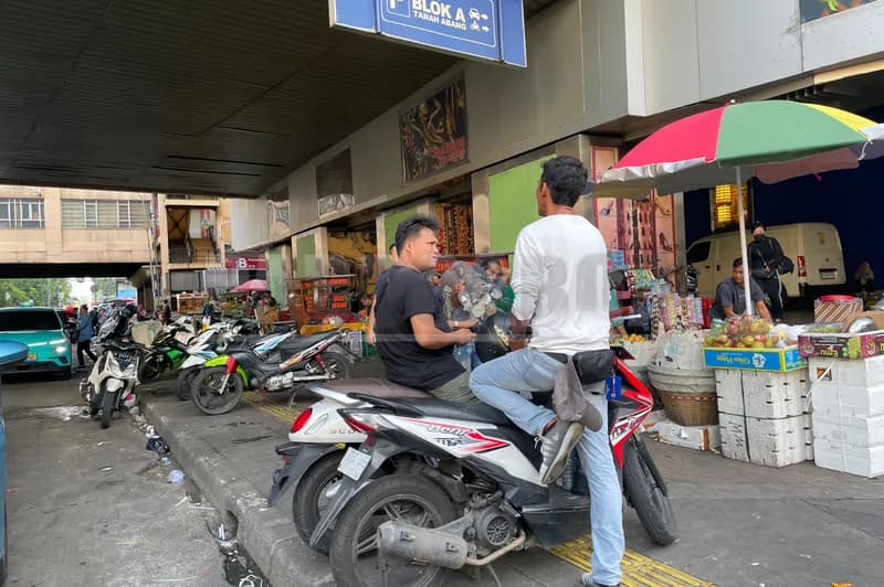 Jukir (berkaos putih) sedang menagih biaya parkir (Foto: PARBOABOA/Defri Ngo)