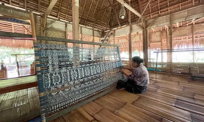 Seorang ibu sedang menata kembali benang-benang yang telah diikat sebelum ditenun menjadi kain (Foto: PARBABOA/Defri Ngo).